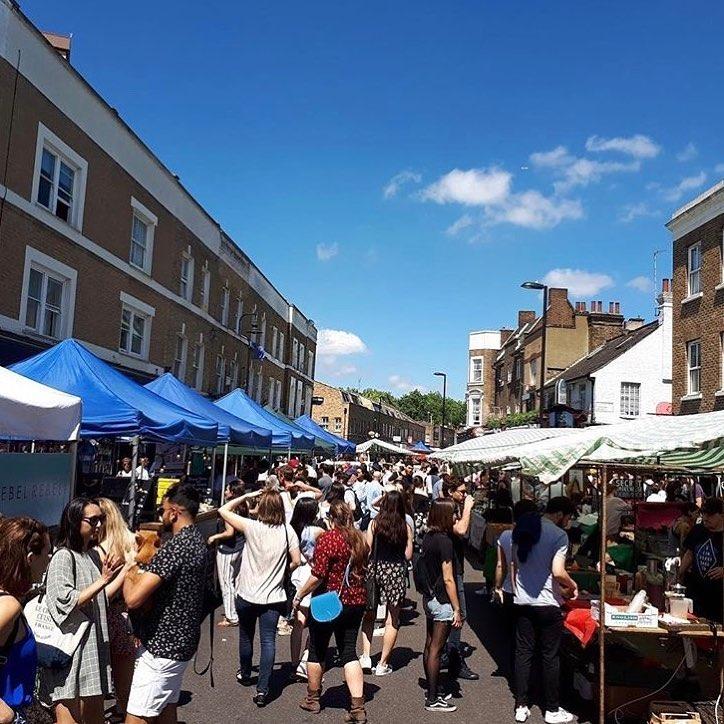 People wandering down Broadway Market in the sun, one of the best weekend markets in London