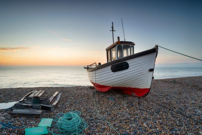 A fishing boat on the beach in Dungeness in Kent, one of the best seaside towns near London 